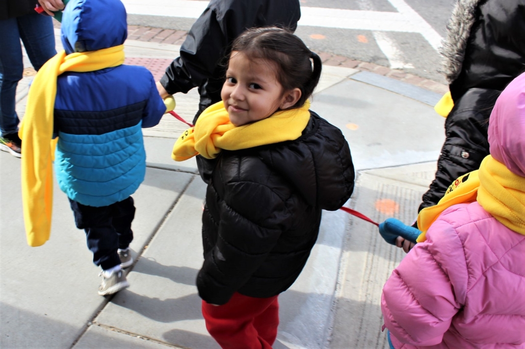 PreK student wearing coat and scarf smiling at the camera